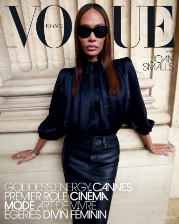 Vogue France cover featuring Joan Smalls in a black satin blouse and leather skirt, accessorized with sunglasses and jewelry, against an architectural backdrop.