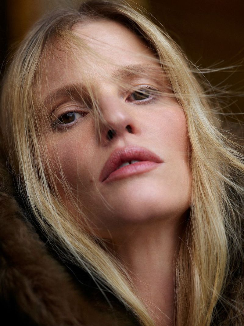 Close-up portrait of a fair-skinned adult woman with light blonde hair, looking directly at the camera in soft, natural light.