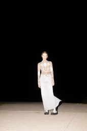 Model standing outdoors at night wearing a patterned top and light skirt for Marc Denim