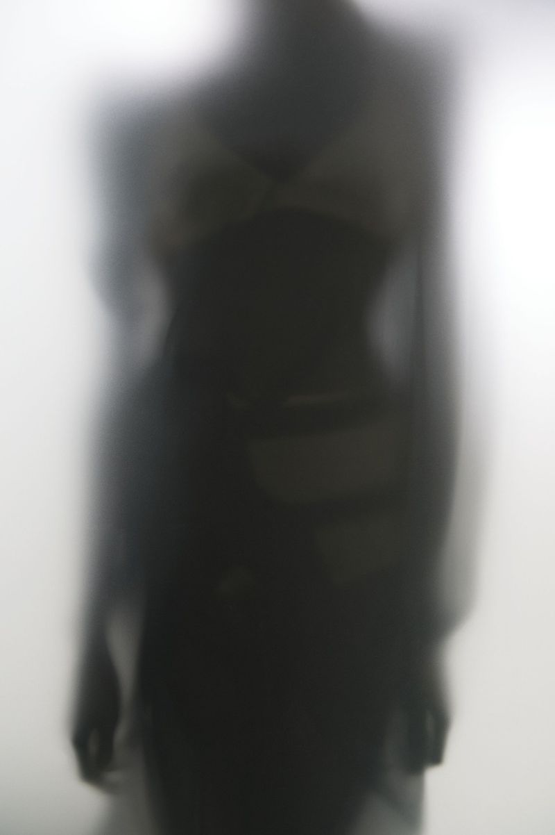 Abstract silhouette of an adult female figure standing behind translucent glass, with a blurred and mysterious effect.
