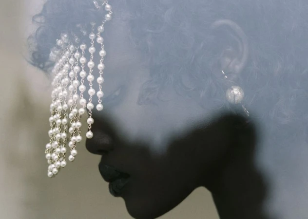 Close-up portrait of model Yar Aguer wearing a cascading pearl headpiece and drop earring for HommeGirls.