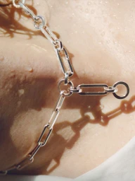 Close-up macro shot of a silver link chain resting on wet skin for Noisé Magazine editorial