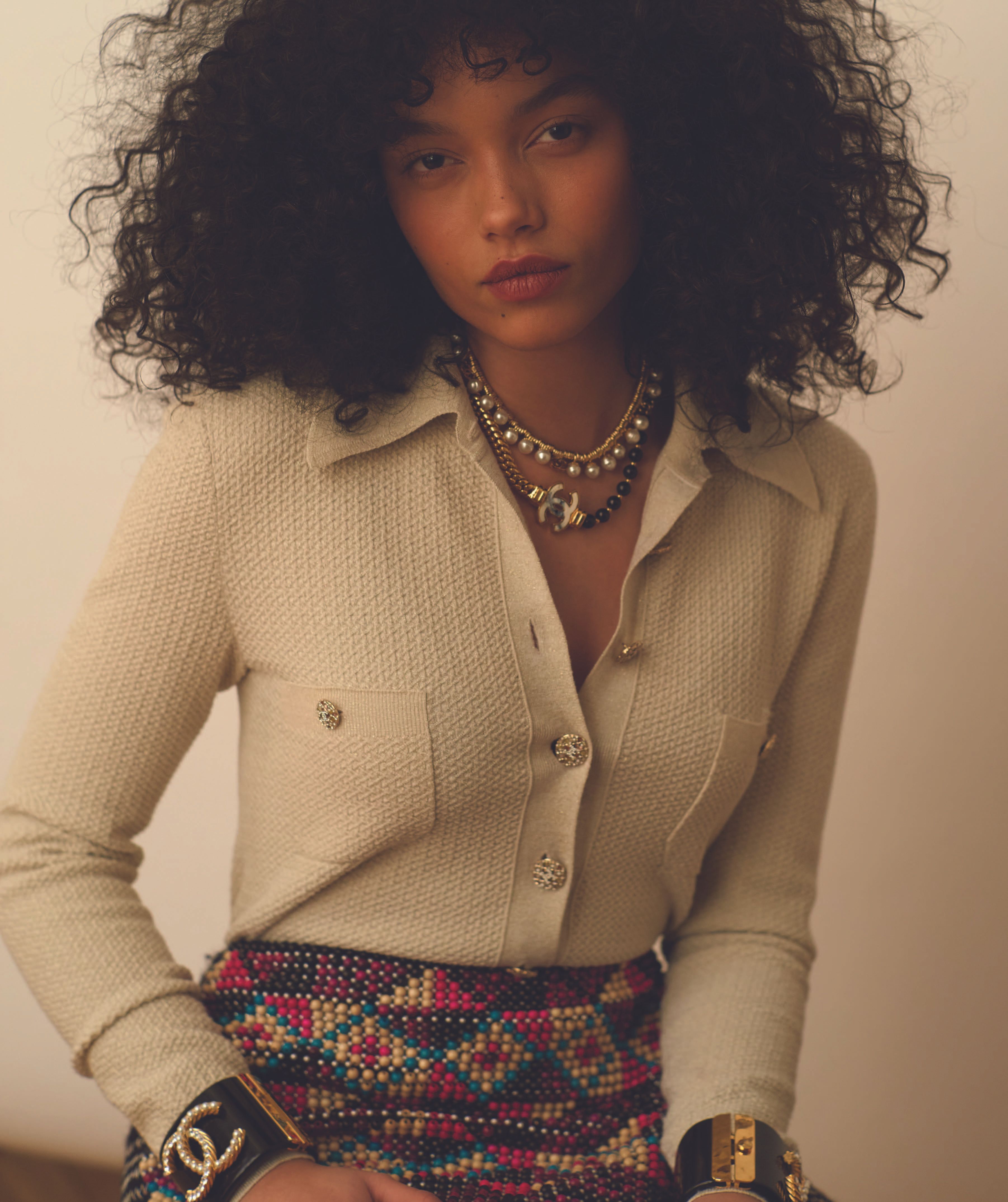 Whitney Peak wearing a cream tweed button-down shirt and patterned skirt with chunky cuffs for Love Want