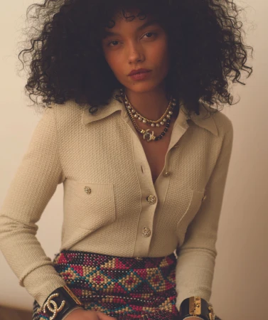 Whitney Peak wearing a cream tweed button-down shirt and patterned skirt with chunky cuffs for Love Want