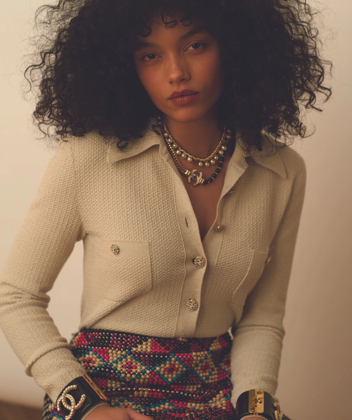 Whitney Peak wearing a cream tweed button-down shirt and patterned skirt with chunky cuffs for Love Want