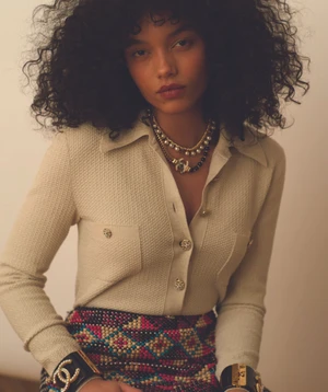 Whitney Peak wearing a cream tweed button-down shirt and patterned skirt with chunky cuffs for Love Want