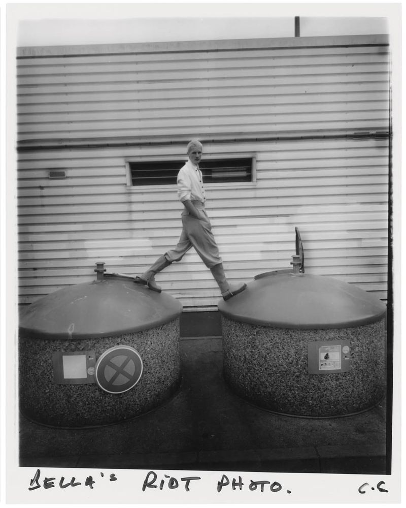 Monochrome photograph of a person walking atop concrete structures, with a siding-covered building in the backdrop, captured in a vintage style.