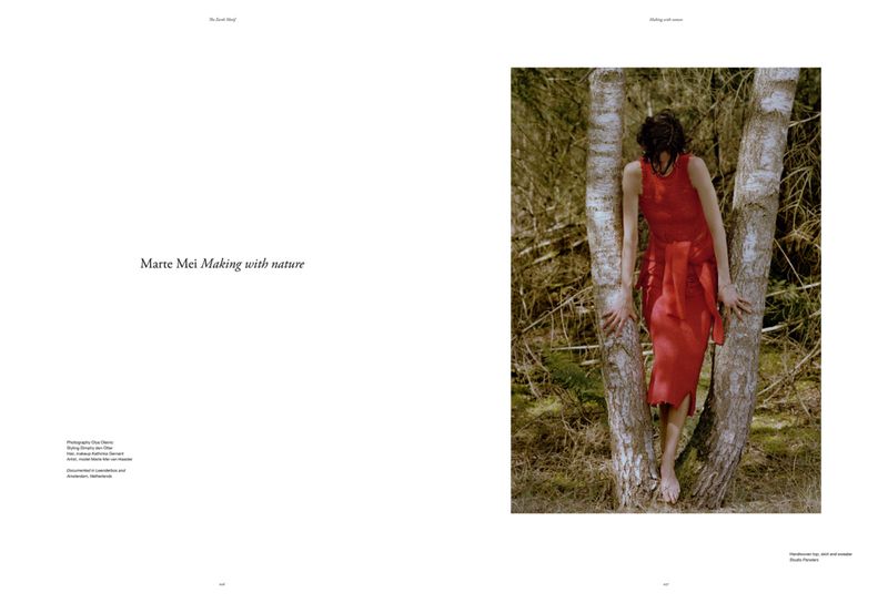 A woman in a red dress embraces a birch tree in a sunlit forest setting, showcased in a fashion-editorial photograph.