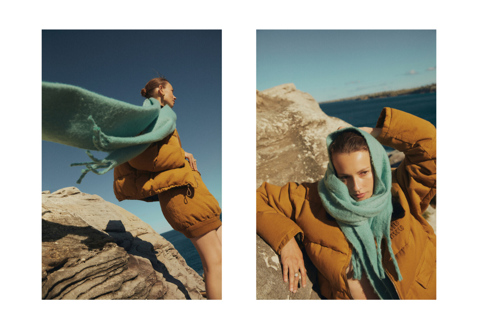 Fashion shot featuring a young woman in an orange puffer jacket and light blue scarf posing on coastal rocks under a clear blue sky.