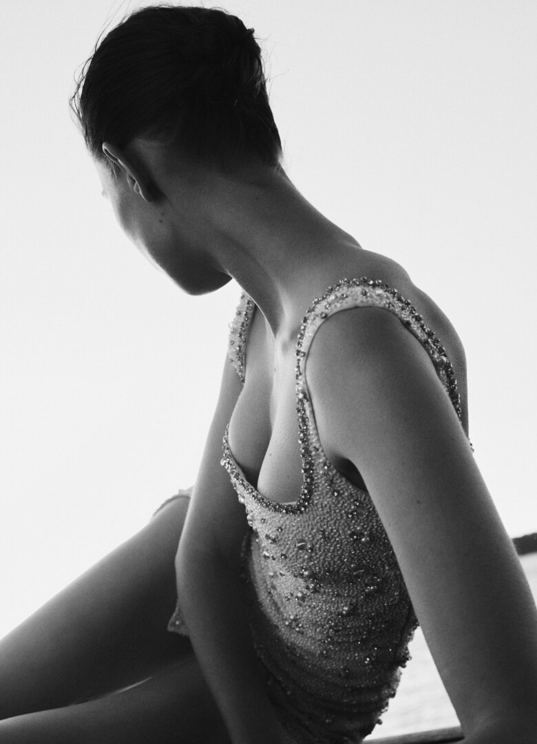 Close-up monochrome portrait of a woman wearing an embellished beaded dress against a bright light background