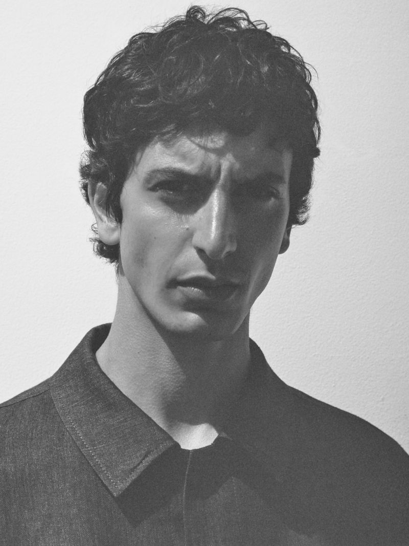 Portrait of a man wearing a dark collared shirt against a plain light background