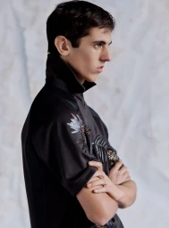Model with arms crossed wearing a black collared top against a light textured backdrop for Le Mile Magazine