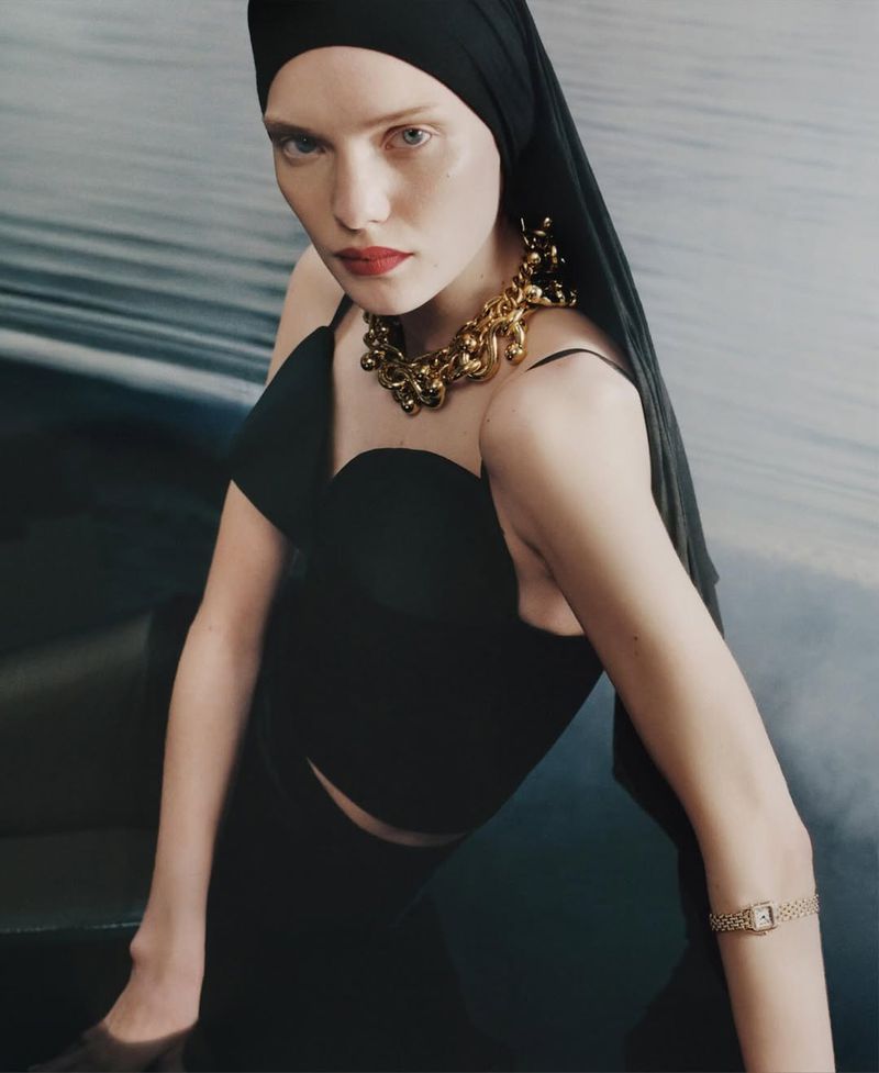 Model in black top and headscarf wearing a chunky gold necklace and watch for M Le magazine du Monde