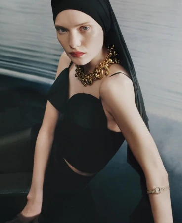 Model in black top and headscarf wearing a chunky gold necklace and watch for M Le magazine du Monde