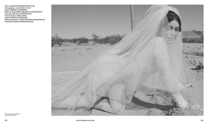 Black and white studio shot of a woman in a wedding dress and veil lying on sand in a desert environment. Editorial fashion.