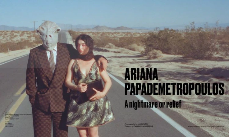 Model Ariana Papademetropoulos poses with a person wearing an alien mask on a desert road in a fashion editorial style photograph.