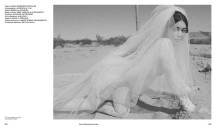 Monochrome image of a woman wearing a white lace bridal veil and bodysuit crawling on a sandy desert terrain.