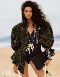 Model wearing a tweed jacket on a sandy beach for Elle China, photographed by Nam J.