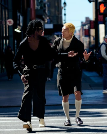 Two male models walking and conversing outdoors on a city street in a fashion editorial by Arturo Alcala for Rouge Fashionbook.