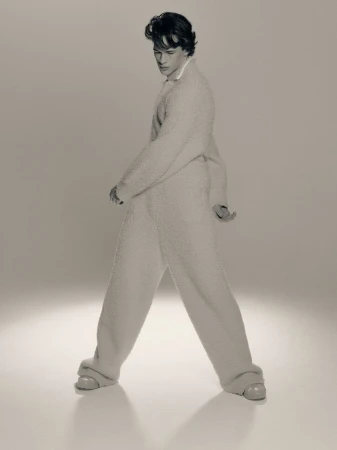 Young adult male fashion model poses in a soft, cream-colored, plush-textured lounge outfit, angled in a studio setting.