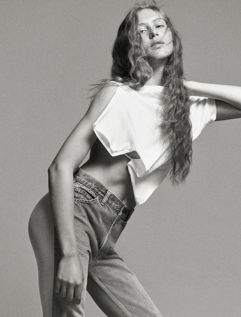 Model Angelina Kendall in a white t-shirt and denim jeans posing against a grey seamless background for Middle Plane Magazine.