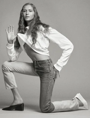 Model Angelina Kendall kneeling in a white top and denim jeans for Middle Plane Magazine, photographed by Mark Kean.