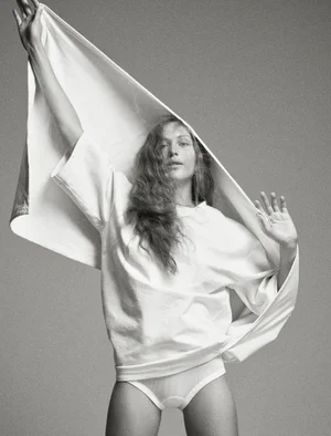 Model Angelina Kendall holding a white t-shirt overhead in a studio editorial portrait