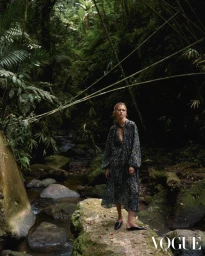 Model standing on mossy rock in lush dense forest next to stream for Vogue Hong Kong Uncharted Paths editorial