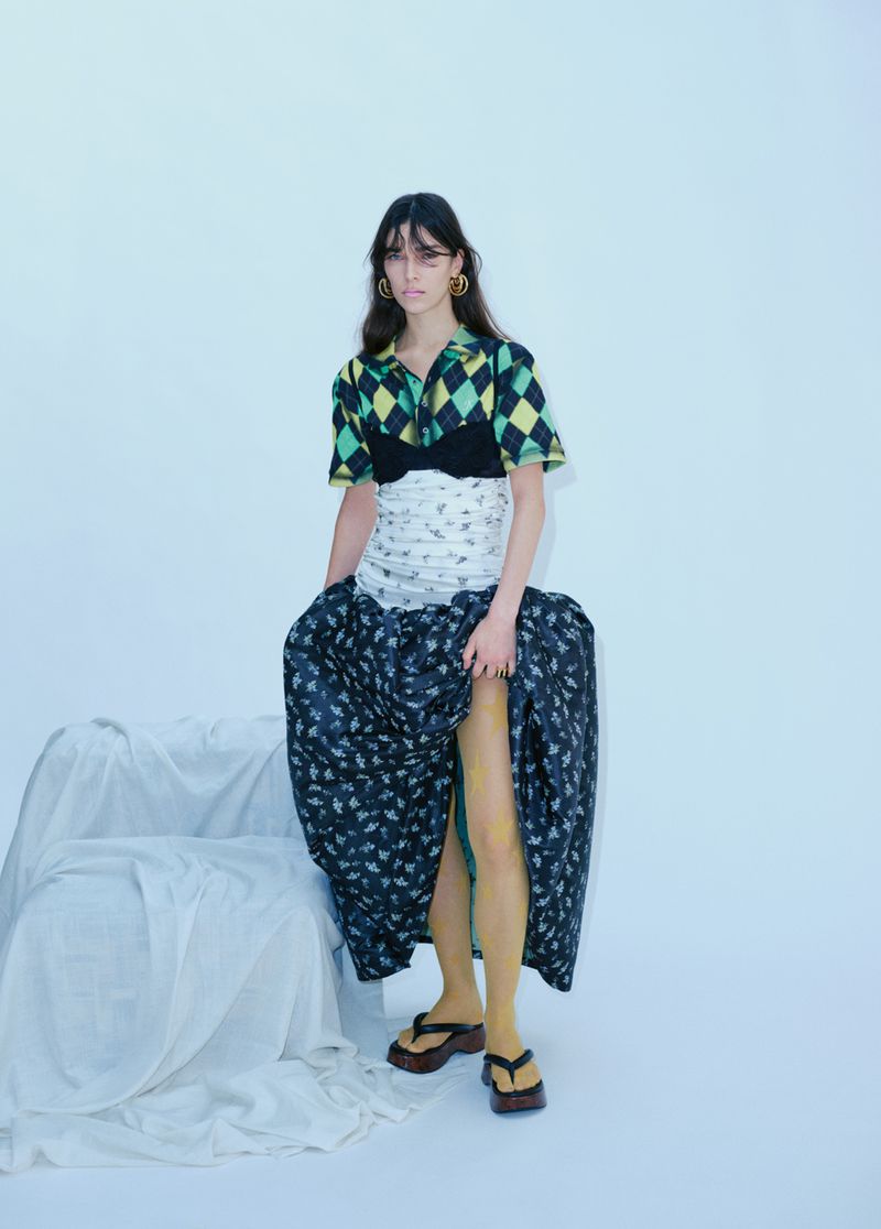 Full-length shot of a woman in a patterned crop top and long skirt, striking a pose in a white photo studio with soft, diffused lighting.