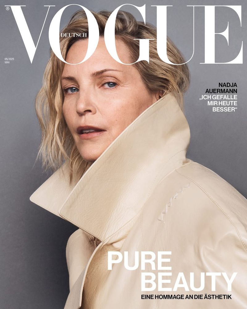 Vogue cover featuring a blonde woman in a light coat looking at the camera with neutral expression and a grey background. 