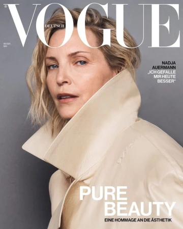 Vogue cover featuring a blonde woman in a light coat looking at the camera with neutral expression and a grey background. 
