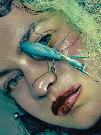 A close-up portrait shot of a fair-skinned adult female model with a striking green mantis insect on her face, beauty lighting, and fashion.