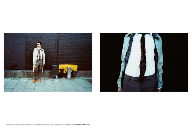 Cole Mohr standing outdoors against a dark brick wall wearing a light coat and holding a yellow flower for AnOther Man Magazine.
