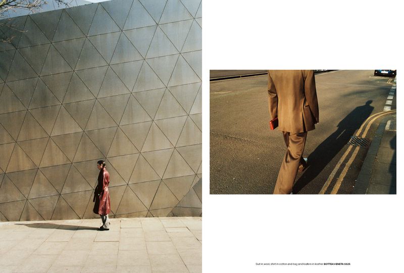 Fashion editorial featuring a woman in a red coat walking past a geometric wall and a man in a brown suit crossing a street.