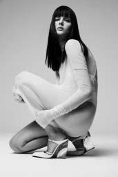 Model Aylah Peterson crouching in sheer white bodysuit and heels for Vogue Netherlands Peekaboo editorial project