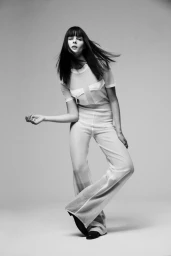Model Aylah Peterson in a white matching top and trousers posing against a grey seamless background for Vogue Netherlands.