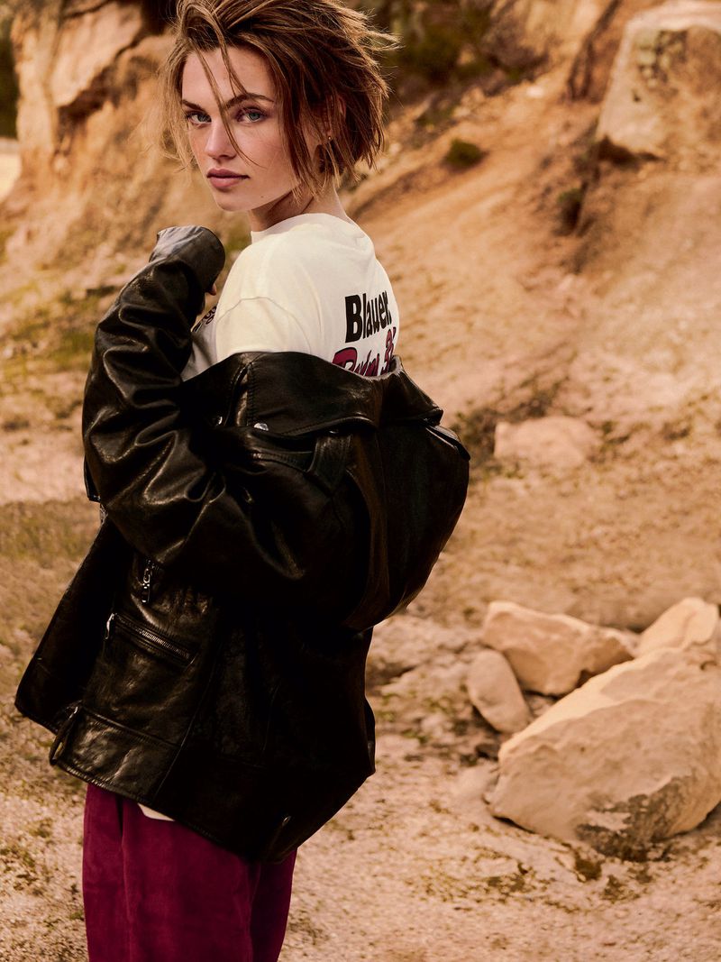 Model Anne Boomgaart wearing a black leather jacket and white t-shirt posing against a rocky outdoor terrain