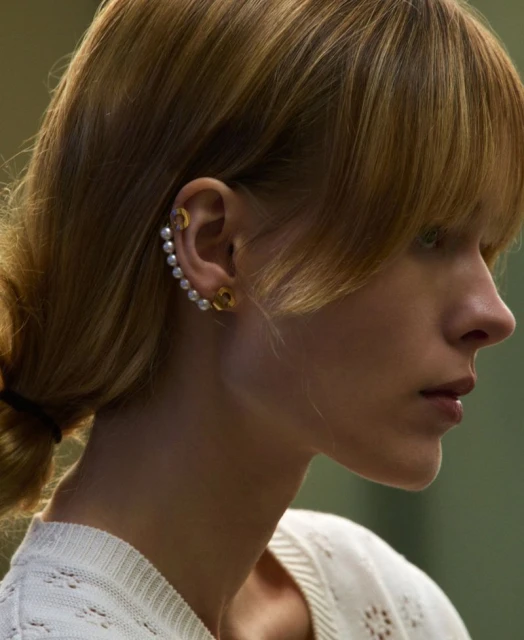 Profile portrait of a woman showcasing pearl and gold ear jewelry. Focus is on the beauty and delicate craftsmanship of the earrings.