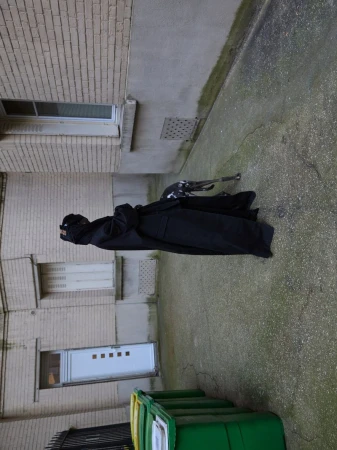 Model Amar Akway in a black coat outdoors against a textured building exterior for Modern Weekly China
