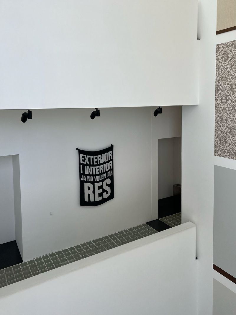 Architectural interior featuring white walls, black light fixtures, and a black banner with white text, creating a minimalist and clean aesthetic.