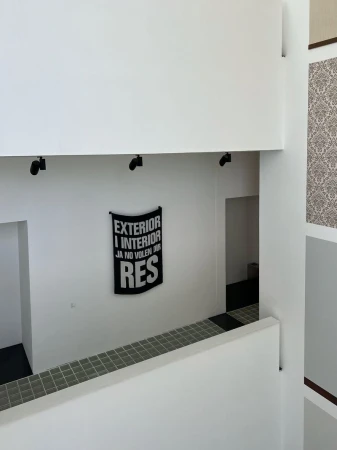 Architectural interior featuring white walls, black light fixtures, and a black banner with white text, creating a minimalist and clean aesthetic.