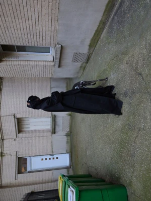 Model Amar Akway in a black coat outdoors against a textured building exterior for Modern Weekly China