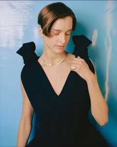 Model wearing a black dress with bow shoulders and diamond jewellery against a blue background for Harper's Bazaar Japan