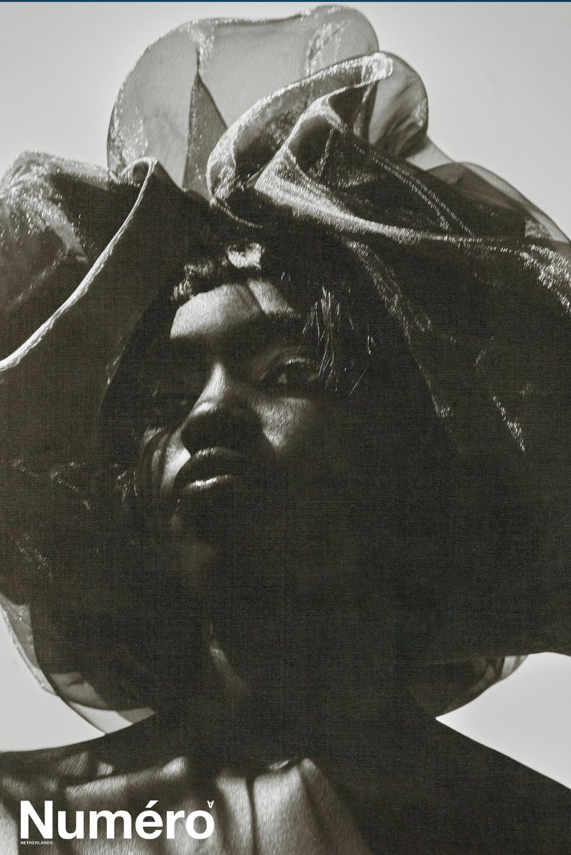 Model Alek Deng wearing a large sheer ruffled headpiece in a high-contrast monochrome fashion portrait for Numero Netherlands.