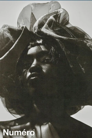 Model Alek Deng wearing a large sheer ruffled headpiece in a high-contrast monochrome fashion portrait for Numero Netherlands.
