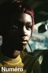 Close-up portrait of model Alek Deng with reddish-brown hair and metallic lipstick seated inside a car for Numero Netherlands
