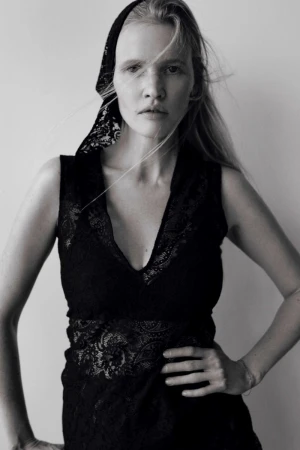 Black and white portrait of a blond adult female wearing a lace top and a headscarf, looking directly at the camera with a neutral expression.