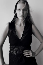 Model Lara Stone wearing a black lace dress and matching head covering against a neutral studio background