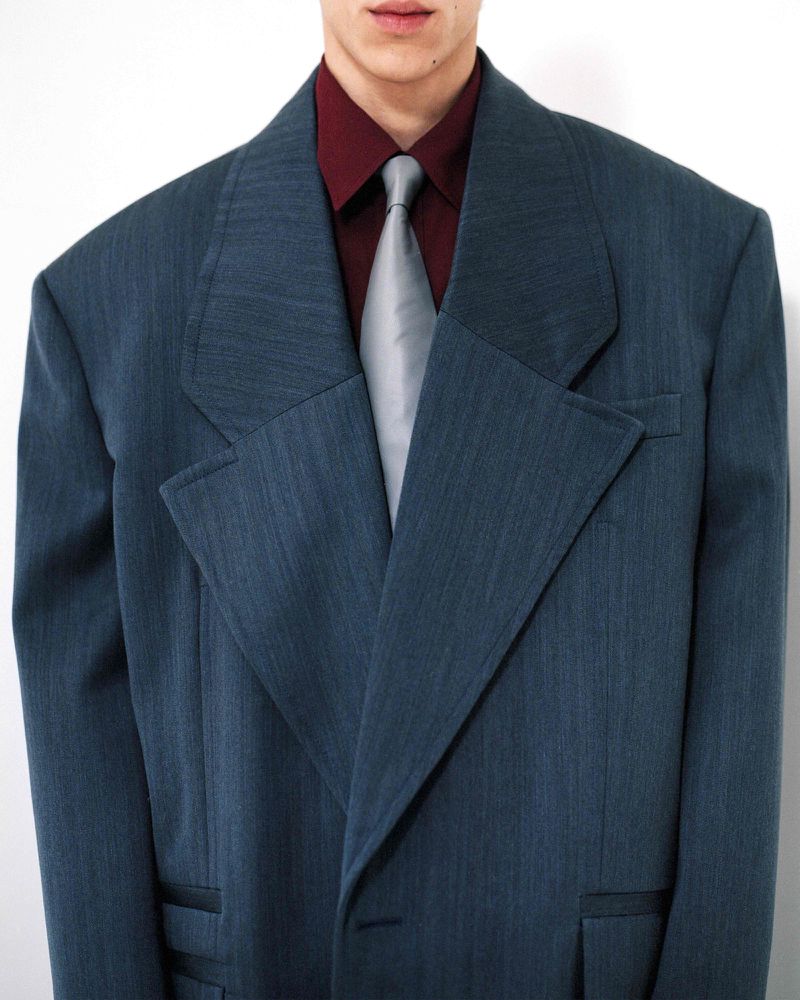 Man in blue suit and maroon shirt with gray tie, minimalist studio shot, fashion advertisement, professional, upscale look, and business.