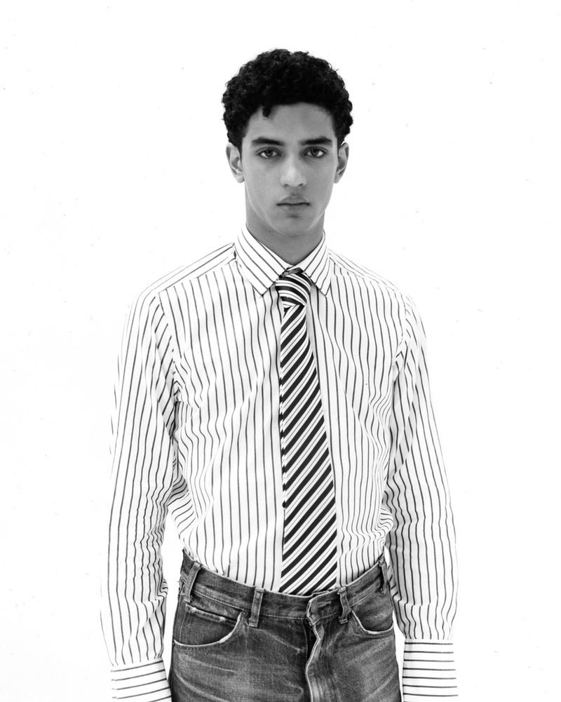 A young man wearing a striped button-down shirt and matching striped tie against a white background